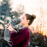 Girl kissing french bulldog puppy outdoors