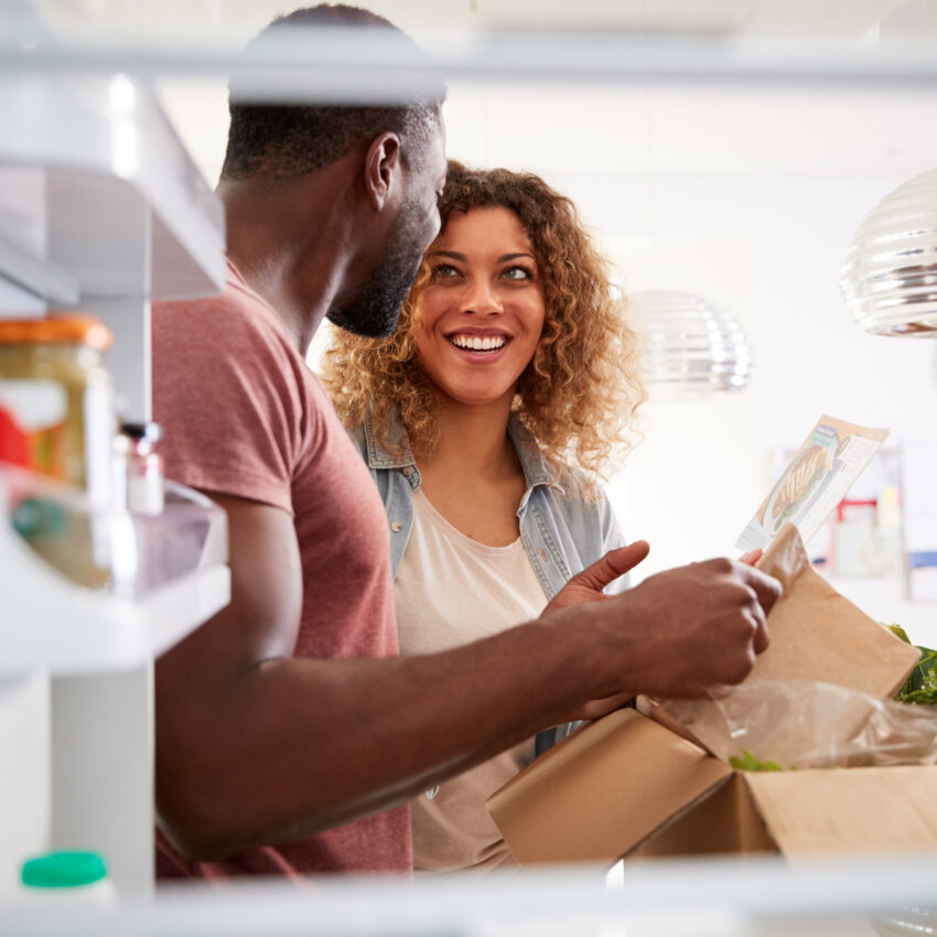 View Looking Out From Inside Of Refrigerator As Couple Unpack Online Home Food Delivery
