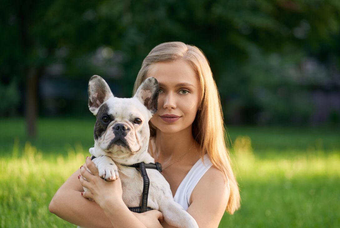 Woman holding french bulldog outdoors
