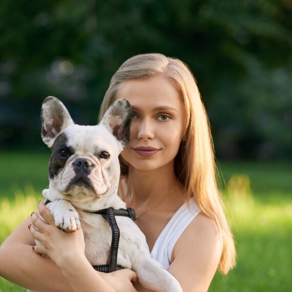 Woman holding french bulldog outdoors