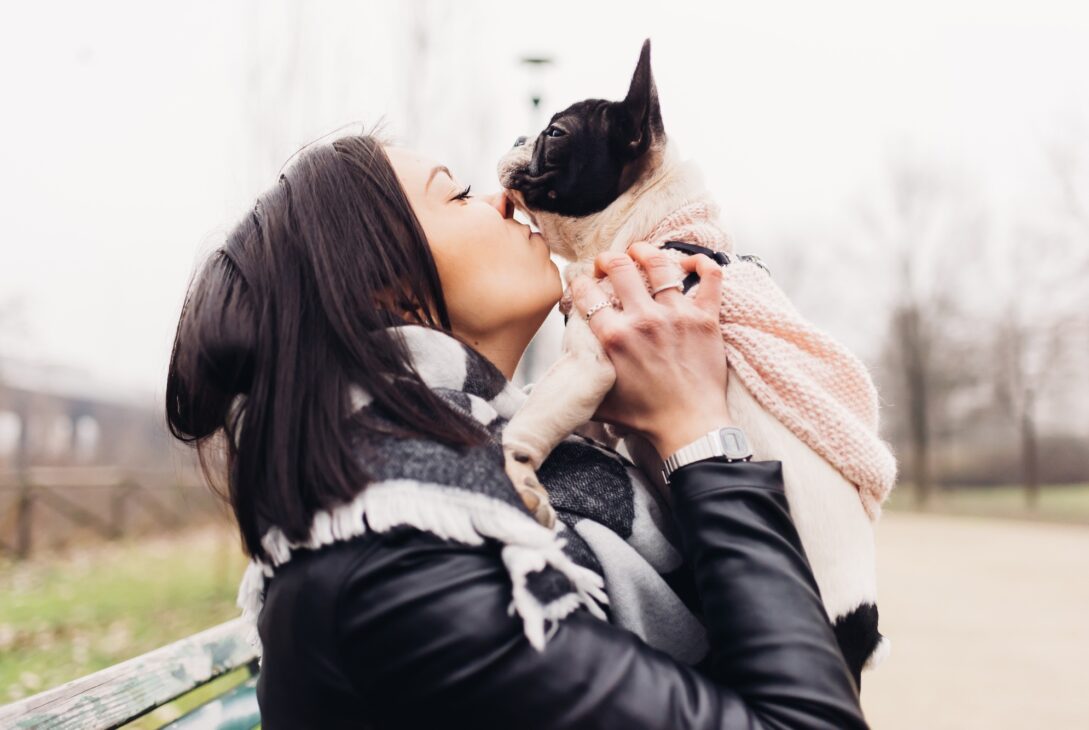 Young beautiful woman kissing her french bulldog