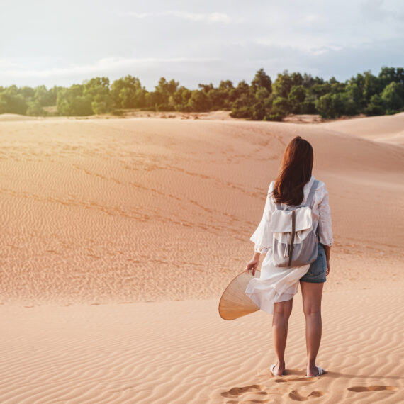 Young woman traveler walking at red sand dunes in Vietnam, Travel lifestyle concept